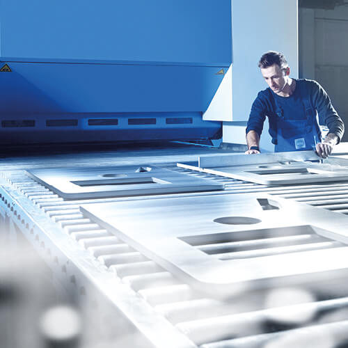 Ein Rostfrei-Stahl-Mitarbeiter betrachtet Metallplatten.